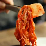 muž drží kus naloženého zelí, tzv. kimchi