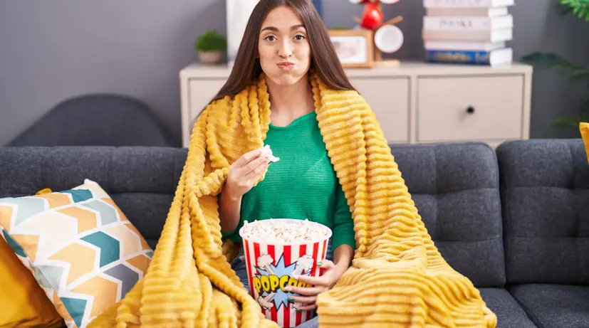 dívka se nacpává popcornem u televize