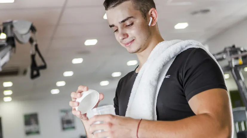 mladý muž ve fitku si připravuje protein