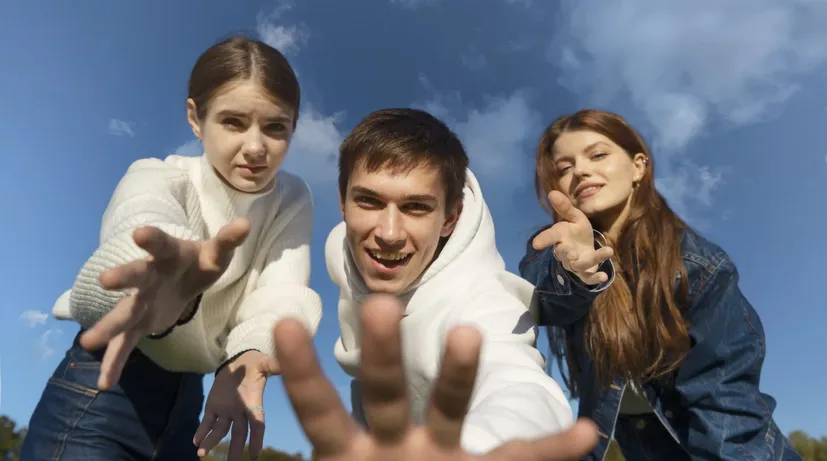 parta mladých lidí se natahují směrem k objektivu