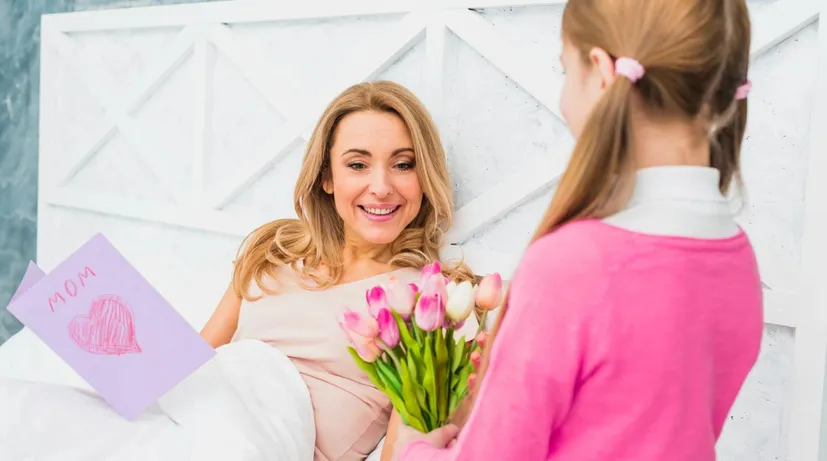 dívka mámě dává přání a květiny ke Dni matek