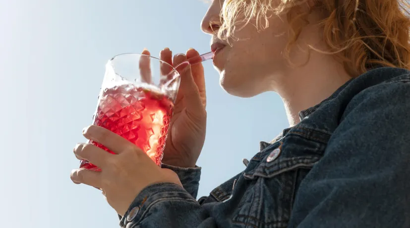 dívka pije drink ve skleničce s brčkem