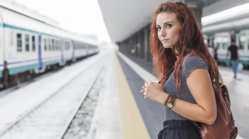 mladá žena na vlakovém nádraží s batohem