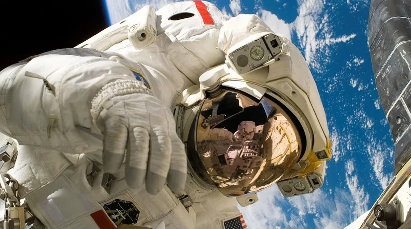 kosmonaut ve vesmíru, za ním planeta Země