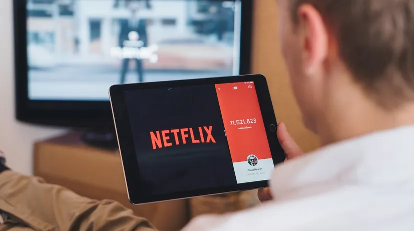 muž se dívá na tablet, kde je velkým písmem Netflix