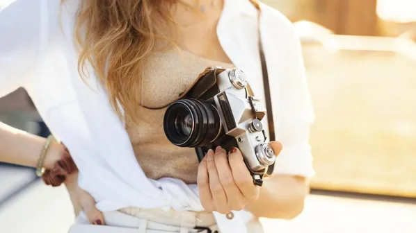 žena v ruce drží svůj fotoaparát venku