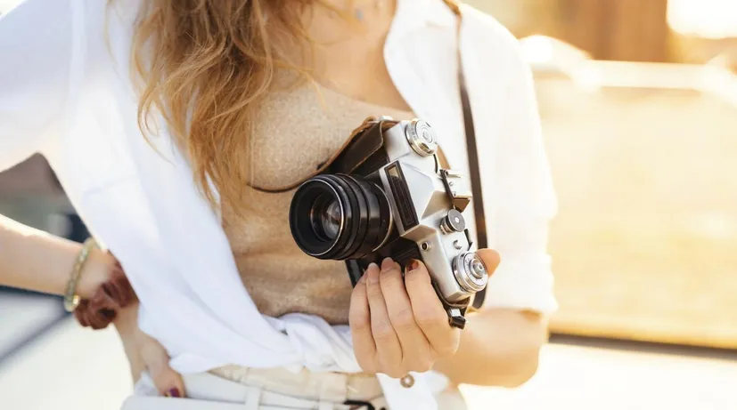 žena v ruce drží svůj fotoaparát venku