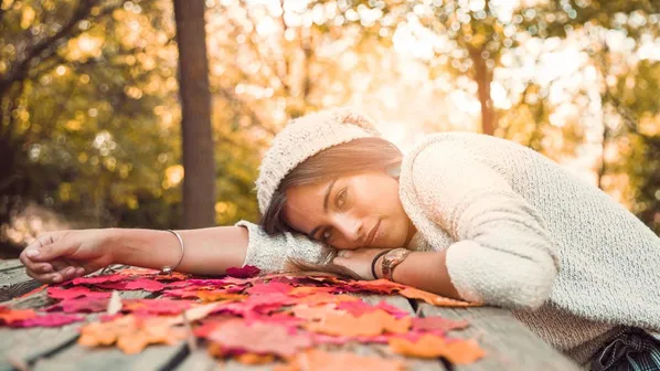žena se opírá o dřevěný stůl v parku, během západu slunce